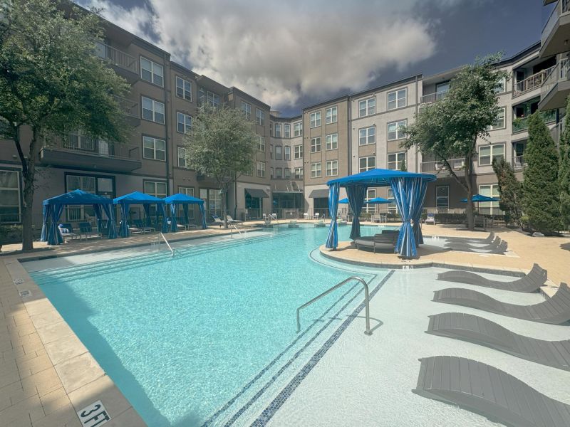 The Civic modern apartment building with large outdoor pool, blue cabanas, and lounge chairs under a partly cloudy sky.